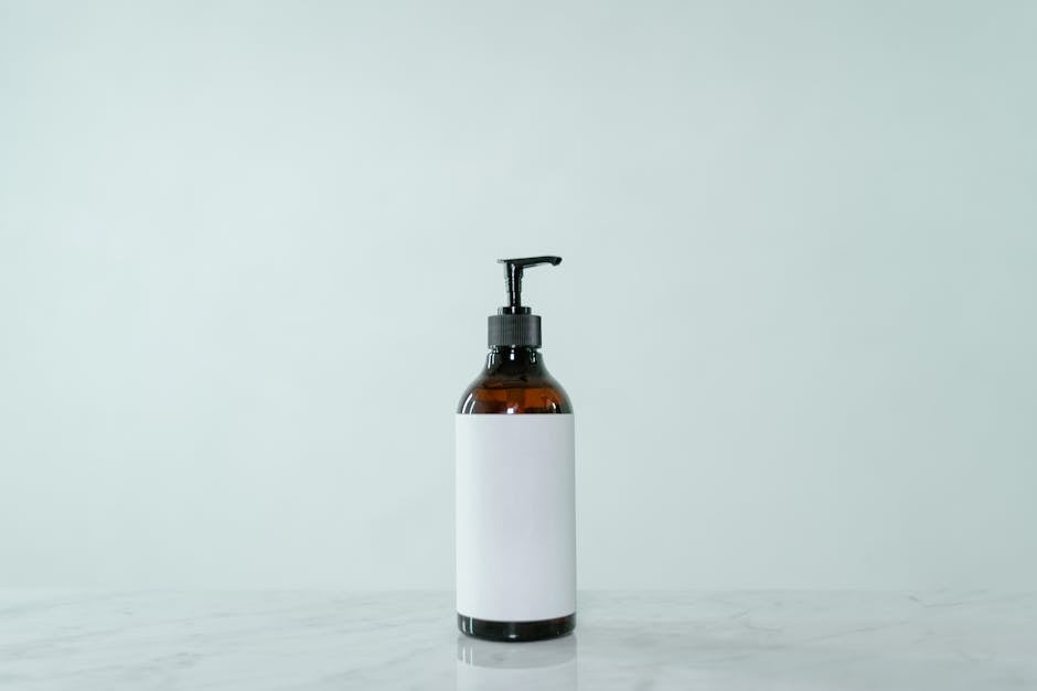 Minimalist display of a brown glass pump bottle with blank label on a light surface.