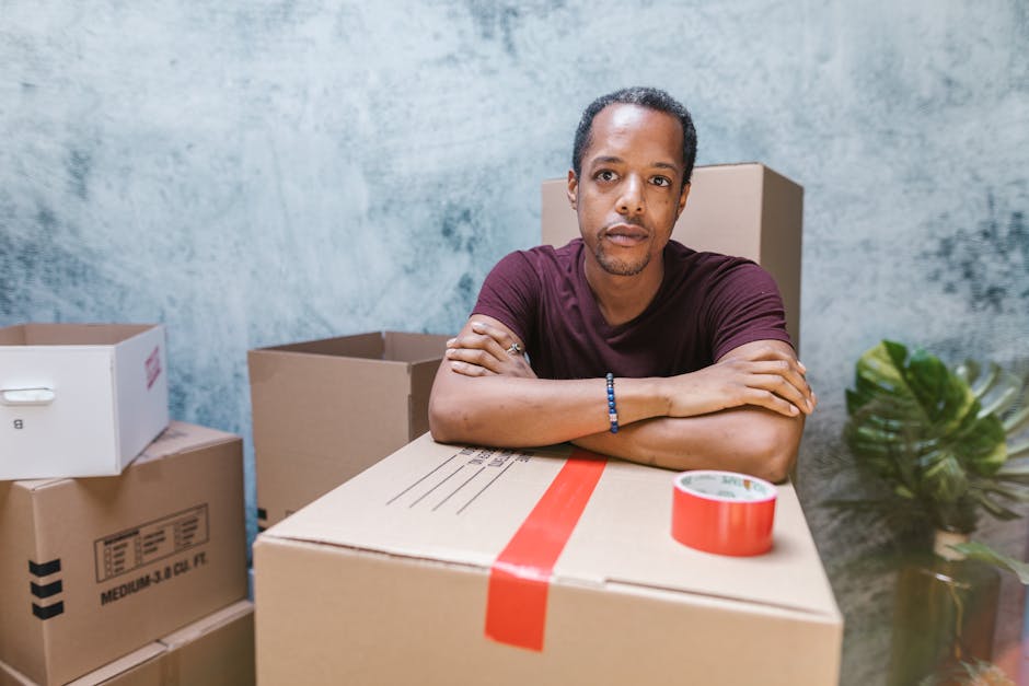 Man stands confidently with packed boxes, symbolizing moving or relocation preparation.