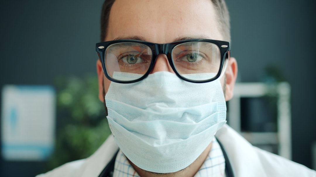 Doctor wearing a mask and glasses looking directly.
