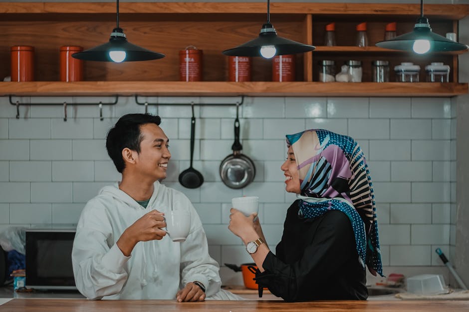 A cheerful couple enjoying coffee in a modern kitchen setting, sharing smiles and conversation.