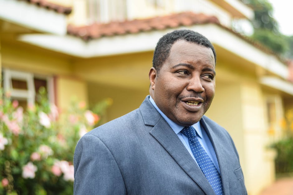 Confident African American man in a suit smiling outside a building with plants.