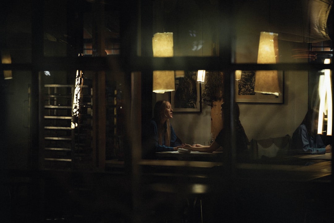 Woman reading at a table in a dimly lit room.