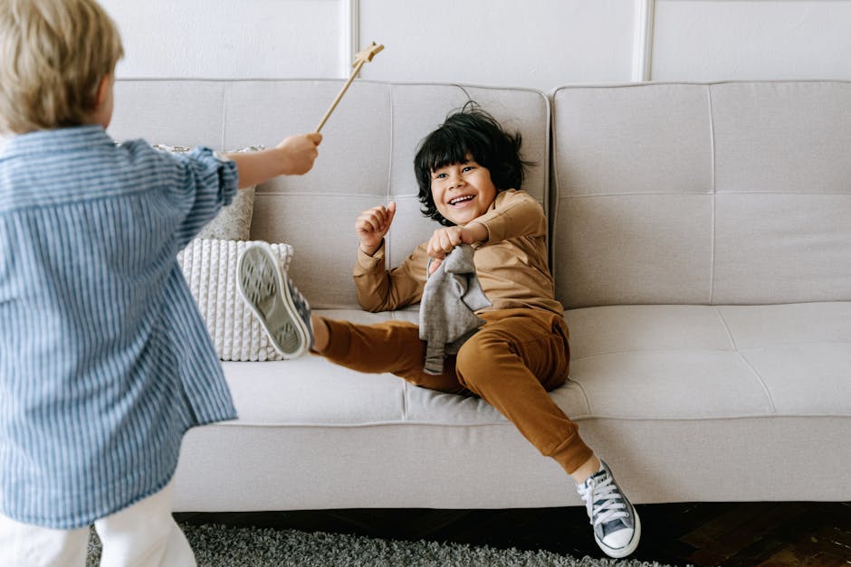 Two children having fun and playing energetically on a sofa, capturing a happy moment indoors.
