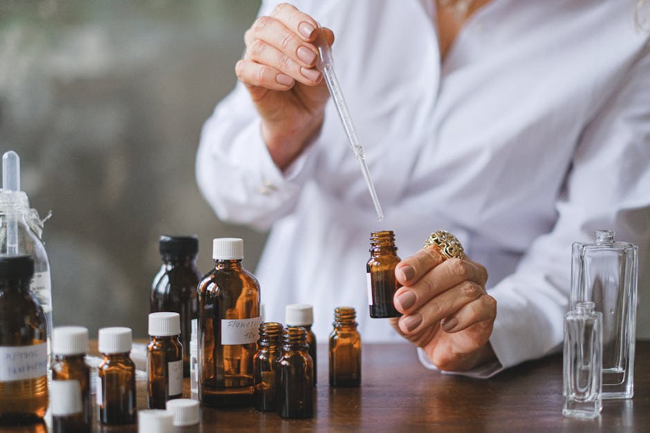 Close-up of hands handling amber glass bottles during an aromatherapy session.