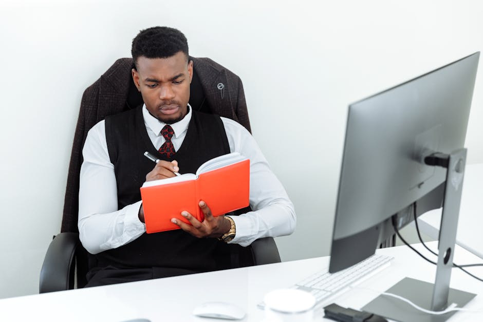 Focused businessman taking notes in an office environment, emphasizing productivity and professionalism.