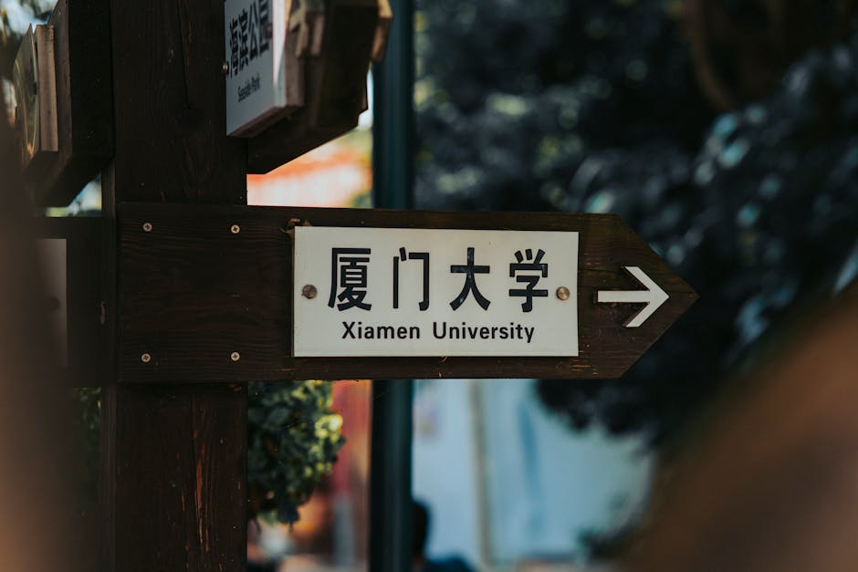 Directional sign pointing to Xiamen University in an outdoor setting.