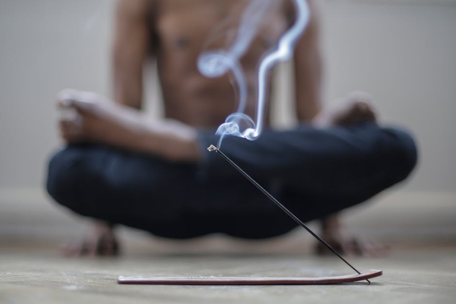 A man meditates with incense smoke creating a peaceful indoor atmosphere.
